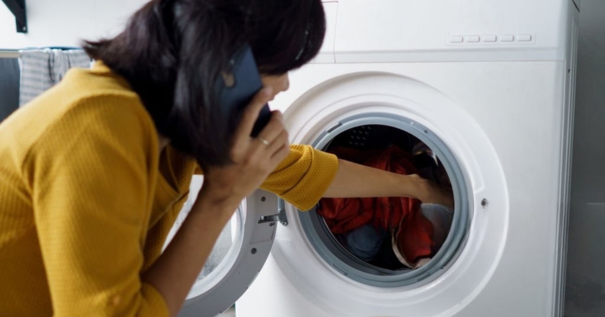 A frustrated woman on the phone checking her LG front-load washer, which is not spinning properly. Common causes include an unbalanced load, a faulty lid switch, a worn-out drive belt, or a clogged drain pump. If your LG washer isn't spinning, try redistributing the load or calling a professional for repair