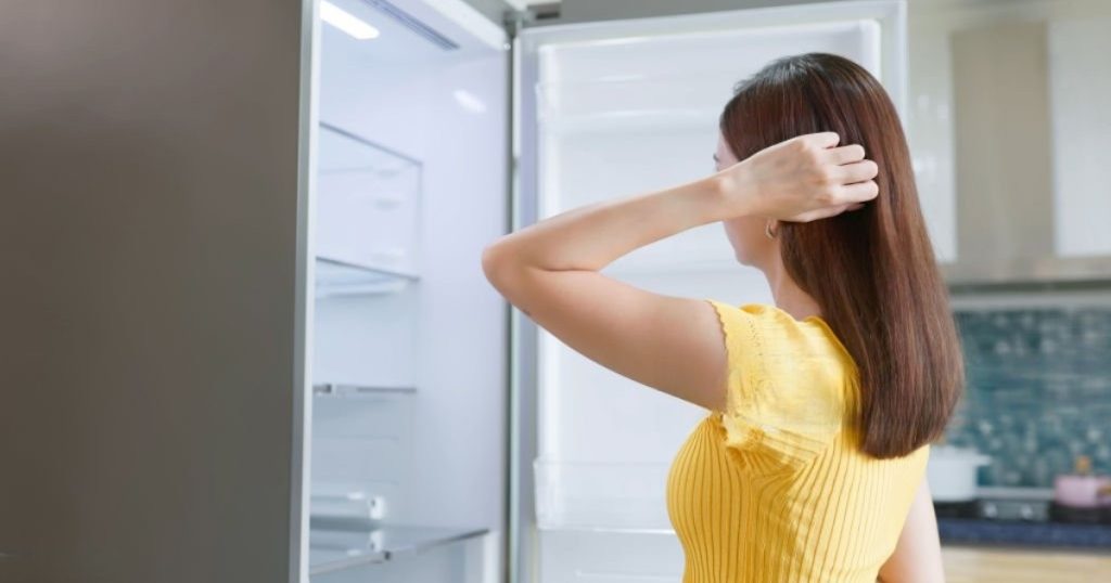 Woman puzzled while looking at an empty refrigerator that's not cooling. Common reasons for a fridge not cooling include dirty condenser coils, a faulty thermostat, a malfunctioning evaporator fan, or blocked air vents. Learn troubleshooting tips and expert repair solutions to restore your refrigerator’s cooling efficiency