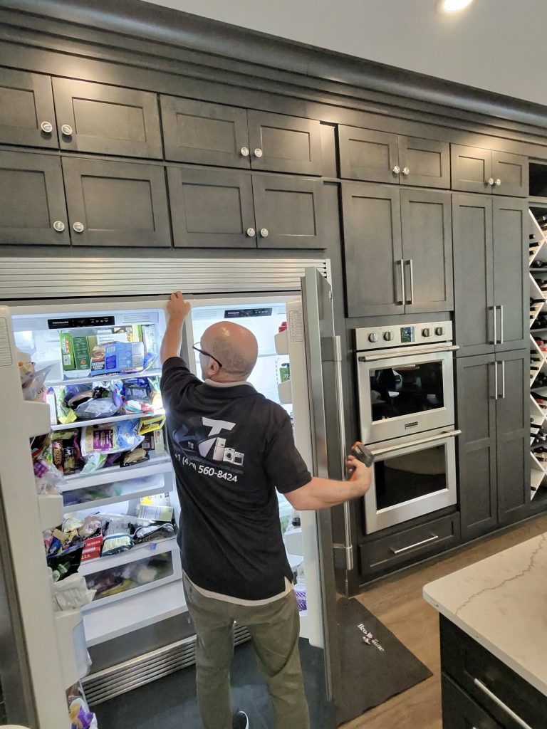 AT Appliance Services technician diagnosing a built-in refrigerator in Cumming, GA