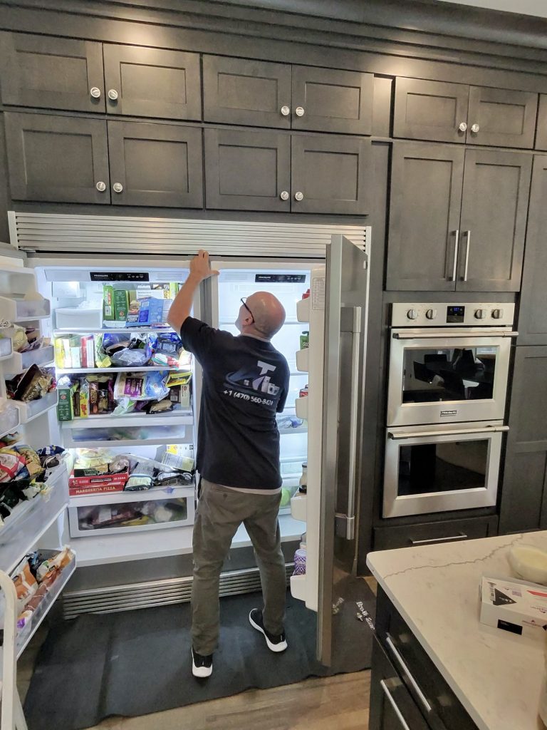 AT Appliance Services technician repairing a built-in refrigerator in Cumming, GA
